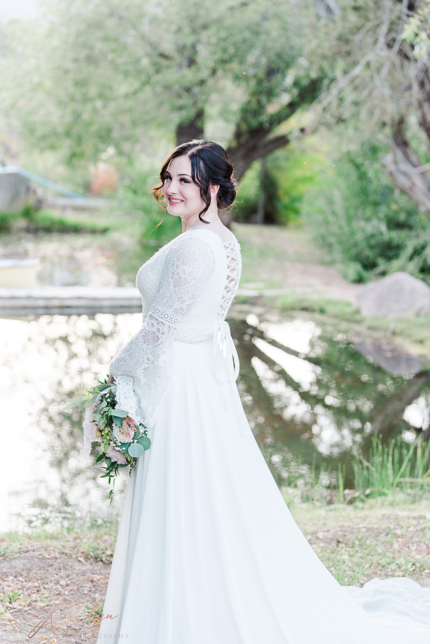 Sunset wedding at New Harmony Utah. Bride in wedding attire standing near a willow pond.