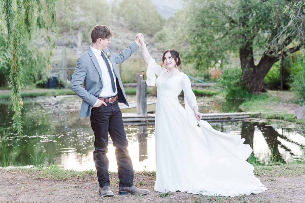 Sunset wedding at New Harmony Utah. Couple in wedding attire standing near a willow pond.
