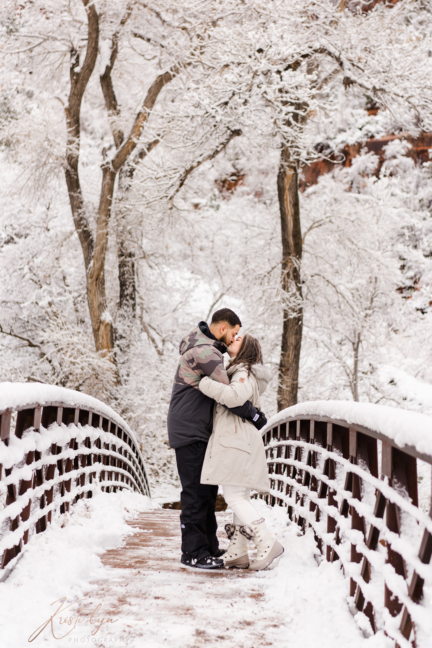 Couple kissing on a snowy bridge